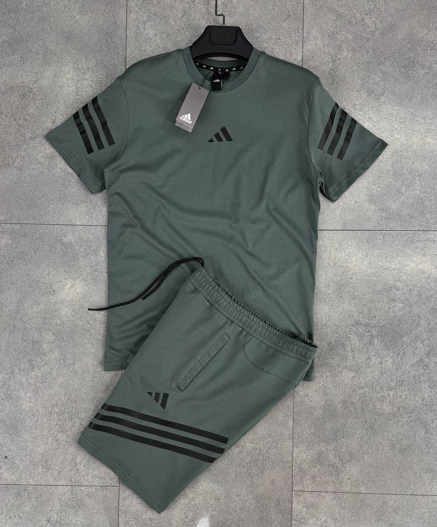 Prémium minőségű Adidas férfi szett, amely rövidnadrágból és zöldesszürke csíkos pólóból áll.